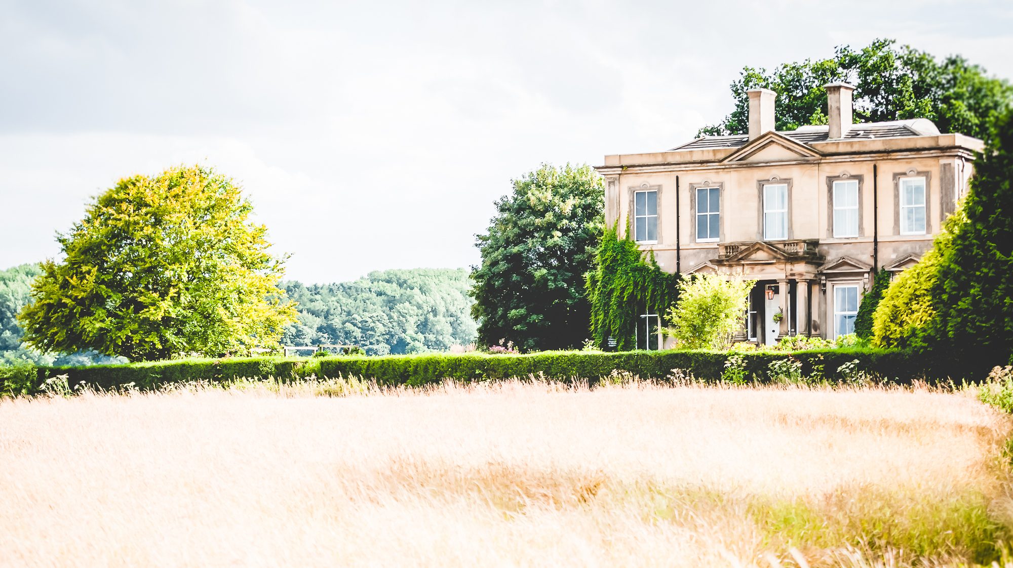 Hothorpe hall exterior image with fields and trees in shot