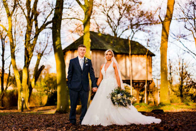 Man and woman standing in woodlands holding flowers