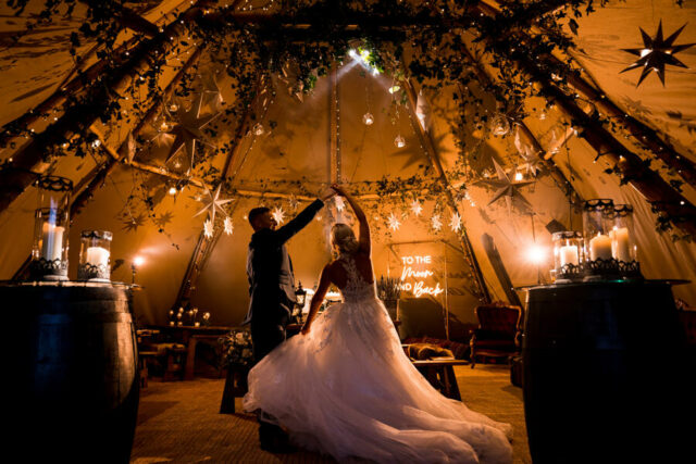 Newly married couple dancing in winter tipi with warm lighting