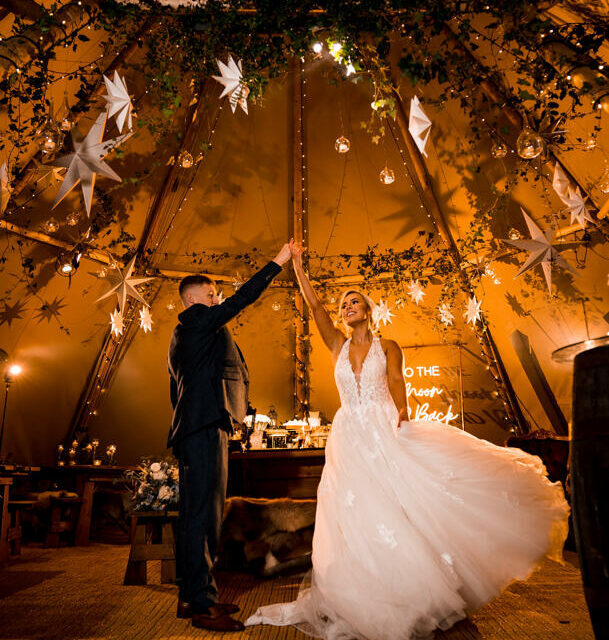 Newly married couple dancing in winter tipi with warm lighting